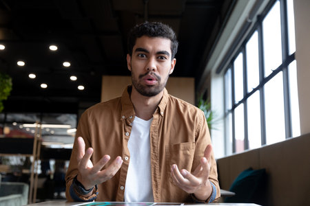 Mixed race businessman talking gesturing on video call in creative office. social distancing in business office workplace during covid 19 coronavirus pandemic.の写真素材