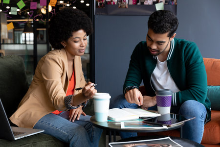Happy diverse businessman and businesswoman drinking coffee on their break in office. social...