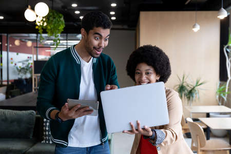 Happy diverse businessman and businesswoman using laptop and tablet in office. technology teamwork in business office workplaceの写真素材