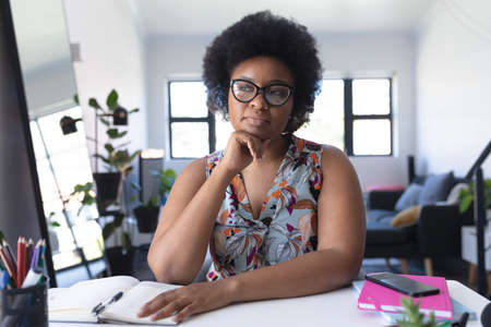 African american female vlogger recording a video rubbing her chin. self isolation technology communication at homeの写真素材
