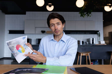 Caucasian businessman sitting having video chat going through paperwork in modern office. business modern office workplace technology.の写真素材