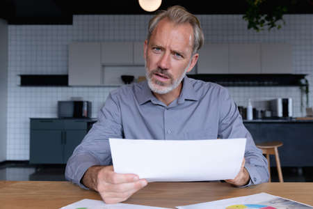 Caucasian businessman sitting having video chat going through paperwork in modern office. business modern office workplace technology.の写真素材