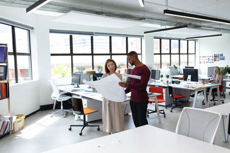 Diverse male and female colleague looking at blueprints and discussing. business people and work...