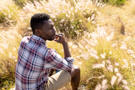 Fit afrcan american man sitting and resting in mountain countryside. healthy lifestyle, exercising in nature.の写真素材