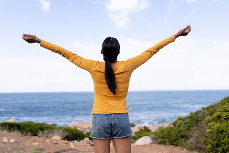 Fit african american woman standing spreading arms in mountain countryside. healthy lifestyle,...