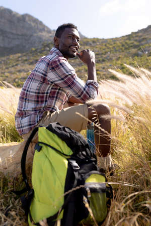 Fit afrcan american man sitting and resting in mountain countryside. healthy lifestyle, exercising...