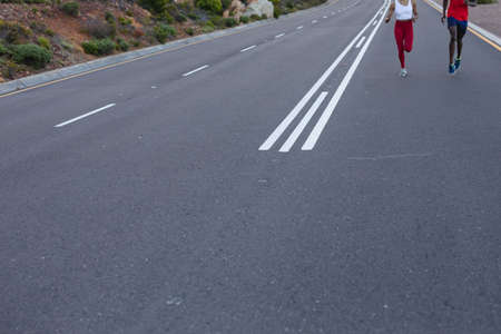 Fit african american couple in sportswear running on a coastal road. healthy lifestyle, exercising in nature.の写真素材