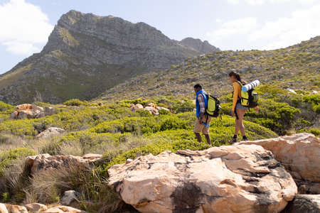 Fit afrcan american couple wearing backpacks hiking on the coast. healthy lifestyle, exercising in nature.の写真素材
