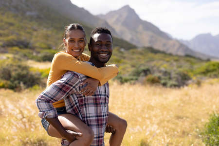 Fit african american couple resting and embracing in mountain countryside. looking at the camera and smiiling. healthy lifestyle, exercising in nature.の写真素材