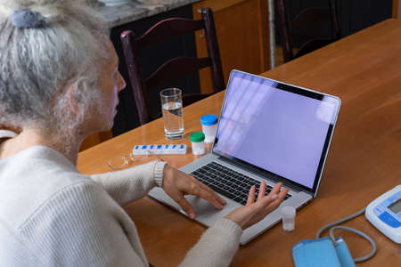 Senior caucasian woman having video call medical consultation using laptop in kitchen. telemedicine...