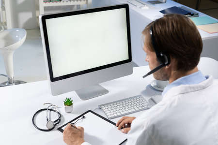 Caucasian male doctor making consultation video call using computer and headset. telemedicine online...