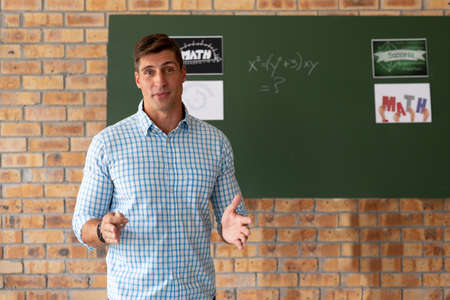 Portrait of male caucasian teacher teaching mathematics in the classroom at school. distance...