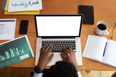 Overhead view of african american woman using laptop while working from home. staying at home in...