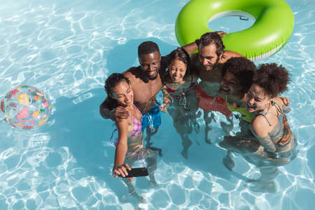 Diverse group of friends having fun and taking selfie in swimming pool. hanging out and relaxing...
