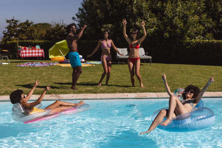 Diverse group of friends having fun and dancing at a pool party. Hanging out and relaxing outdoors in summer.の写真素材