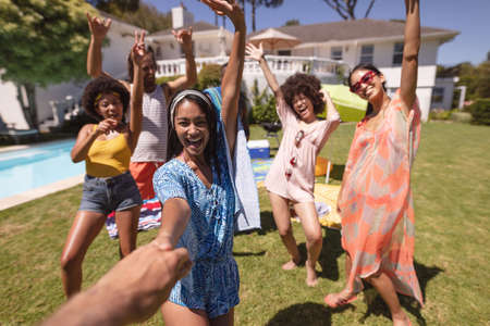 Diverse group of friends having fun and smiling at a pool party. Hanging out and relaxing outdoors...