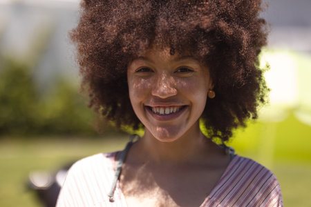 Portrait of mixed race woman looking at camera and smiling. Hanging out and relaxing outdoors in summer.の写真素材