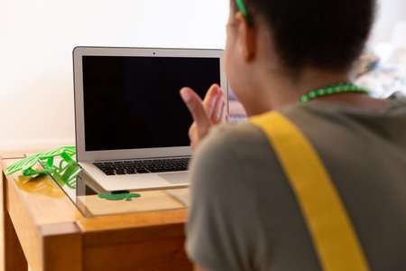 Mixed race woman celebrating st patrick's day making video call blowing kiss. staying at home in...