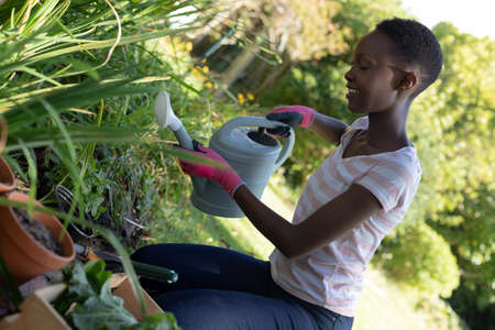 African american woman gardening and smiling on sunny garden terrace. staying at home in isolation...