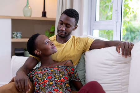 African american couple sitting on sofa embracing. staying at home in isolation during quarantine...