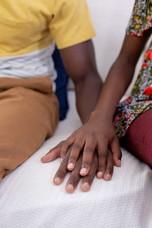 African american couple sitting on sofa holding hands. staying at home in isolation during quarantine lockdown.の写真素材