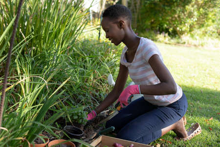 African american woman gardening and smiling on sunny garden terrace. staying at home in isolation...