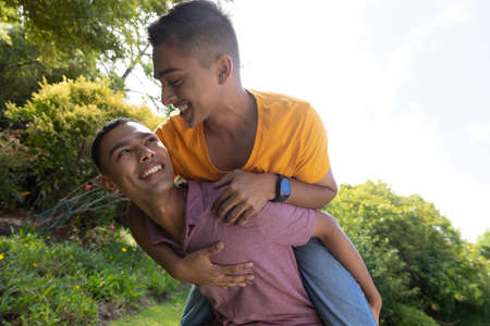 Diverse gay male couple spending time in garden embracing and smiling. staying at home in isolation during quarantine lockdown.の写真素材