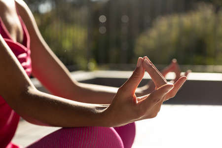 Mixed race woman exercising practicing yoga on a terrace. staying at home in isolation during...