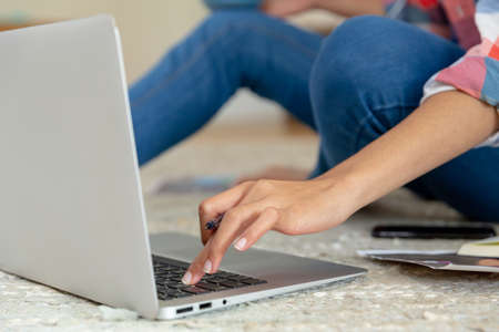 Mixed race woman sitting on the floor working from home using laptop. staying at home in isolation...