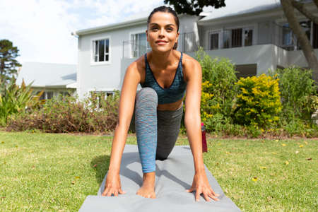 Caucasian woman exercising practicing yoga in garden. staying at home in isolation during quarantine...