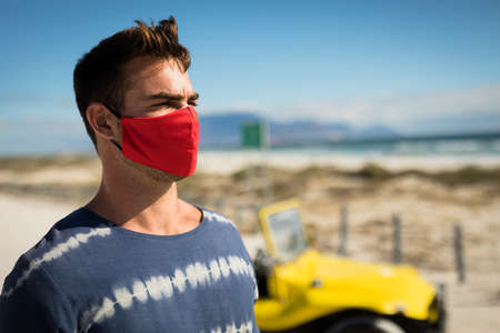 Happy caucasian man wearing face mask next to beach buggy looking toward sea. beach stop off on...