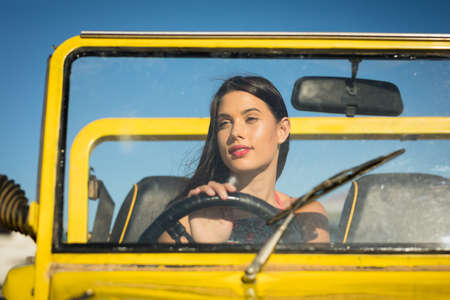 Happy caucasian woman sitting in beach buggy by the sea. beach break on summer holiday road trip.