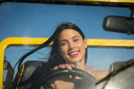 Happy caucasian woman sitting on beach buggy by the sea looking to camera. beach break on summer...