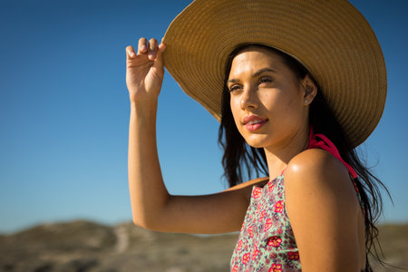 Portrait of caucasian woman by the sea wearing straw hat looking ahead. healthy outdoor leisure time...