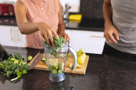 Diverse couple in kitchen making health drink. staying at home in isolation during quarantine lockdown.の写真素材