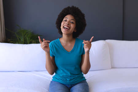 African american woman sitting on sofa making a video call and smiling. staying at home in isolation...