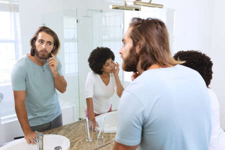 Diverse couple standing in bathroom applying face cream. staying at home in isolation during...