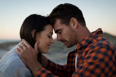 Happy caucasian couple on beach at the sea touching foreheads. love, romance and beach break summer...
