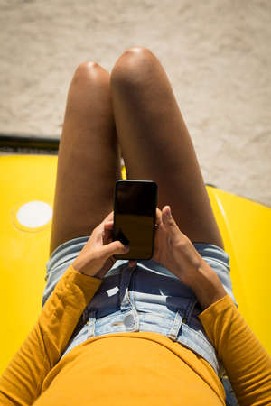 Midsection of caucasian woman lying on a beach buggy by the sea using smartphone. beach break on...