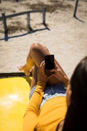 Midsection of caucasian woman lying on a beach buggy by the sea using smartphone. beach break on summer holiday road trip.の写真素材