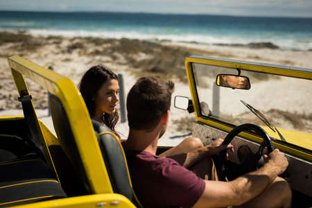 Happy caucasian couple sitting in beach buggy by the sea talking. beach break on summer holiday road...