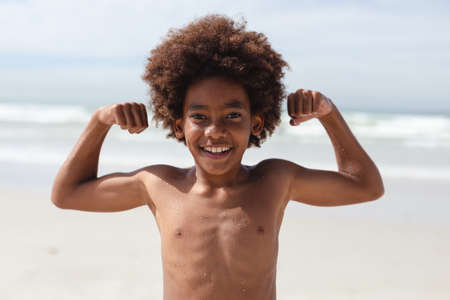 Portrait of african american boy flexing his biceps at the beach. travel vacation summer beach conceptの写真素材