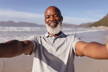 Portrait of african american man taking a selfie on the beach. travel vacation retirement lifestyle conceptの写真素材