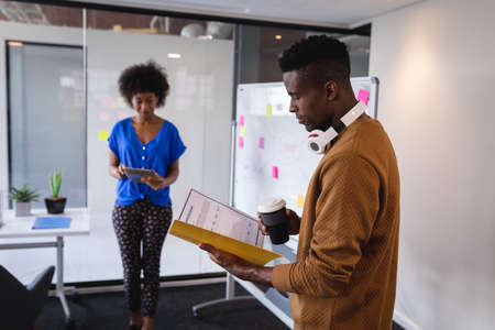 Diverse male and female colleagues standing in front of whiteboard having discussion. independent...