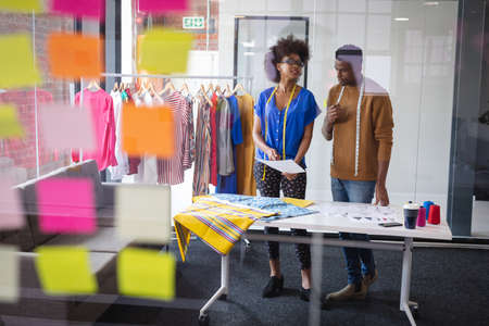 Diverse male and female fashion designers at work discussing and looking at sketches. independent creative design business.の写真素材