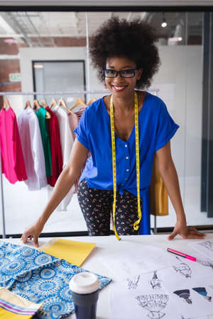 Happy mixed race fashion designer working in office with tailor centimeter on neck. independent creative design business.の写真素材