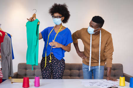 Diverse male and female fashion designers at work discussing and looking at clothes. independent...