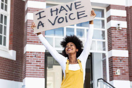 Portrait of mixed race woman holding placard. equal rights and justice protestors on demonstration march.の写真素材