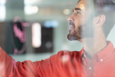 Portrait of caucasian businessman standing and making notes on glass wall. independent creative design business.の写真素材