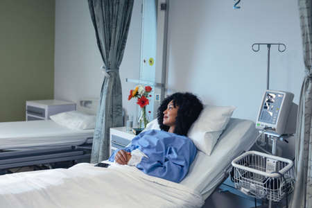 Smiling african american female patient lying in hospital bed looking to side. medicine, health and...